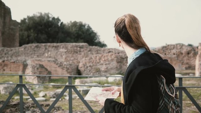 Woman goes in Rome, Italy, looks on map. Girl crossing lower floor of an antique and vast Roman palace - Domus Augustana