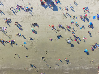 Aerial view beach shoreline on sunny summer day with people bathing, sunbathing, playing volley and relax in Galveston, Texas. Colorful umbrellas, lounge chairs. Holiday maker, summer vacation concept