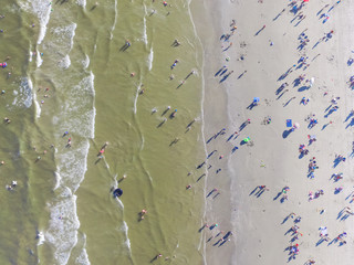 Aerial view beach shoreline on sunny summer day with people bathing, sunbathing, playing volley and...