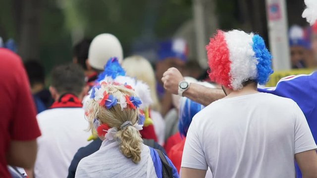 Female and male supporters wearing funny colored headwear walking to stadium