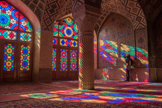 Unidentified woman traveler photograph the colorful light through stained glass window inside Nasir Al-Mulk (Pink Mosque), a traditional mosque in Shiraz, Iran.
