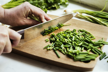 Closeup of hands with knife cutting fresh organic vegetable