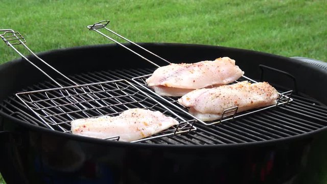 Man's hands cooking fish fillet on grill