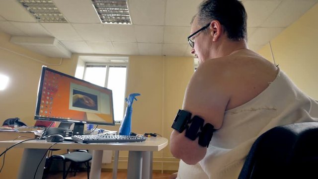 Low angle of the man with the aputated left arm using computer. 4K.