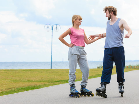 Young couple holding hands while rollerblading