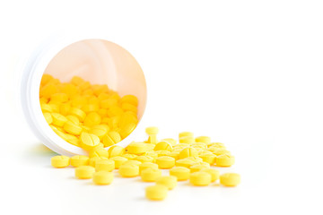Small medicine tablets (or pills) spilling out from the bottle