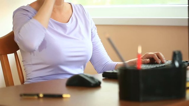 Woman with sweaty armpits. Girl sitting at the working place in office and sweating