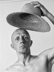 Black and white portrait of a bald man with a straw hat 