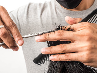 Attractive barber with dark hair doing a haircut for client with scissors isolated on white background.