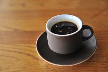 A cup of coffee stands on a brown table in a cafe. A cup of beautiful and fragrant latte with a slice of sugar - a refined sugar and tubules is on the table in a cafe. Cafe inside with visitors and la