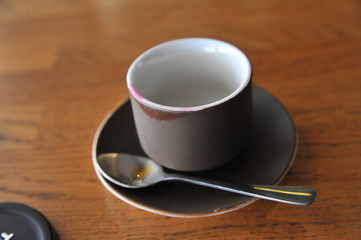 A cup of coffee stands on a brown table in a cafe. A cup of beautiful and fragrant latte with a slice of sugar - a refined sugar and tubules is on the table in a cafe. Cafe inside with visitors and la