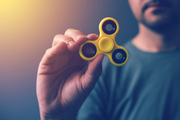 Yellow fidget spinner in male hand