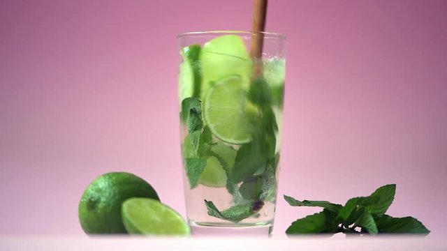 Alcoholic mojito with lime and mint over pink background. 