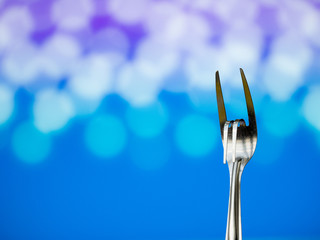 Stainless steel fork is gesture meant to convey love on natural light bokeh background.