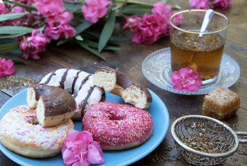 Donuts mit einen Glas Tee und Oleander-Blüten