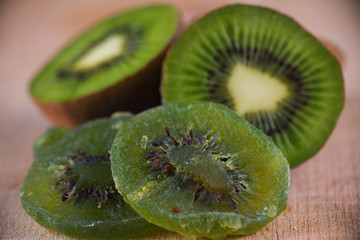 Detail of dried kiwi slices with ripe fruit on wooden background