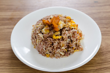 Fried brown rice with eggs and sausages on white dish.