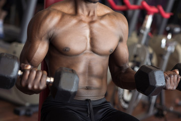 Fototapeta na wymiar black man doing exercises with dumbells in a gym
