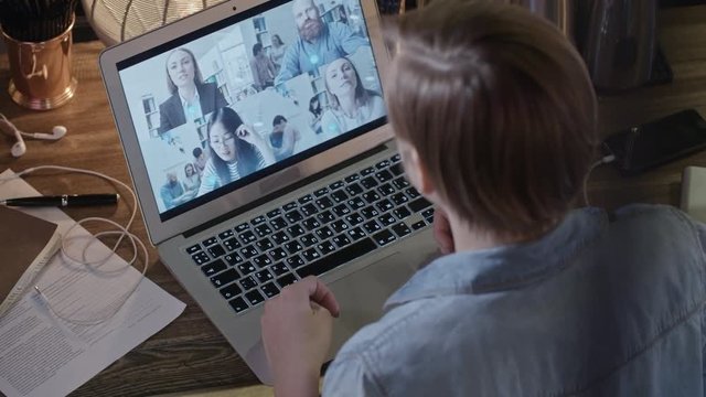 Top view with PAN of young woman with short hair talking with people on video conference call on her laptop 