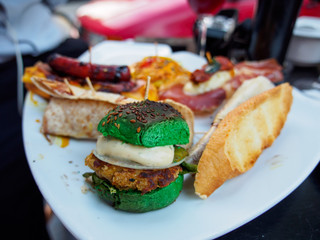 Close-up detail of multiple tapas, Spanish appetizers, in the form of a slider, bread, sausage, and tacos, on a plate outside. Valencia, Spain. Travel and cuisine concept.
