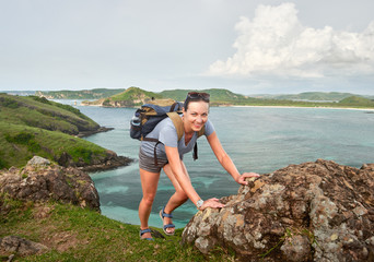 Fototapeta premium Hiker woman with backpack walking on a coast trail in the hills