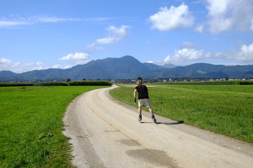 Obraz premium Man rollerblading on rural road, Slovenia