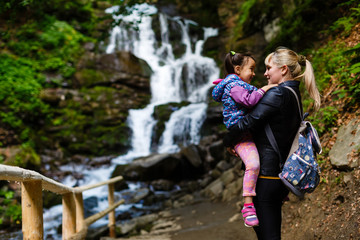 Naklejka na ściany i meble Mother and daughter watching a waterfall