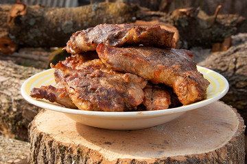 Juicy pork steaks cooked on an open flame grill on big white plate..