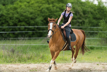 Young pretty girl riding a horse with backlit leaves behind in spring time
