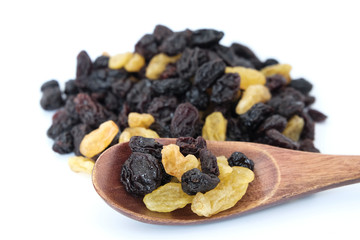 Raisins in a wooden spoon on raisins background. Close-up.
