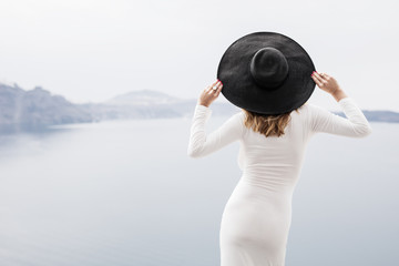 Stylish woman in white dress and black hat from behind