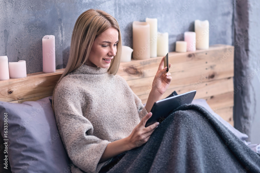 Wall mural Attractive young woman enjoying online shopping in the bedroom