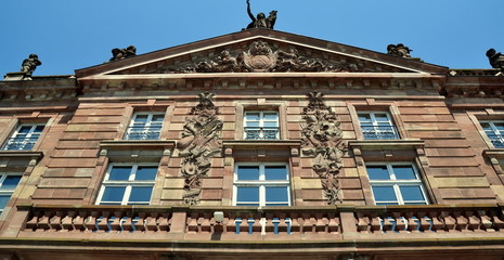 Fassade der Aubette am Kleberplatz mit Giebeldreieck und Balkon vor strahlend blauem Himmel