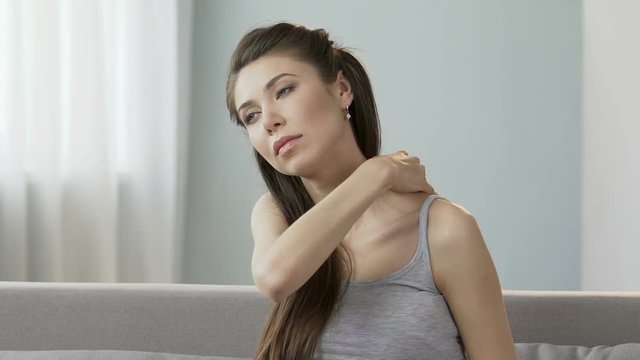 Young female massaging neck and shoulders, releasing disturbing pain, stiff neck