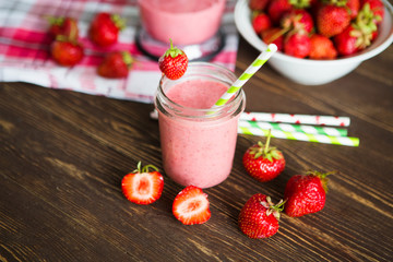 Healthy strawberry smoothie in mug with checkered cloth against rustic wood.