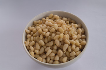 Small white bowl of pine nuts on a grey background