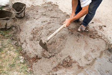 Worker stirs concrete shovel
