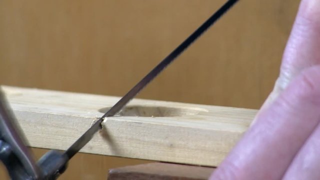 A piece of pine is cut by hand using a coping saw.  Includes audio