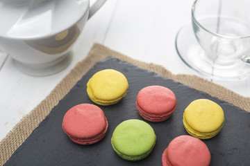 Macarons, tea cup and teapot. Breakfast with sweets.
