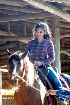 Pretty Asian woman cowgirl riding a horse outdoors in a farm for relax.