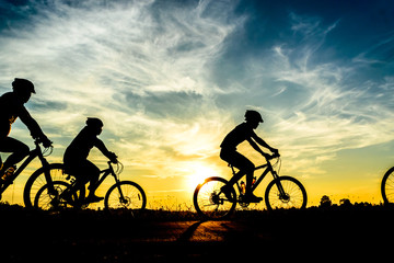 Obraz na płótnie Canvas Silhouette of cyclist riding on bike at sunset.