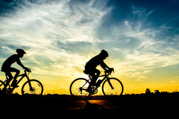 Silhouette of cyclist riding on  bike at sunset.