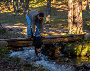 Hombre aguantando chica desde un puente