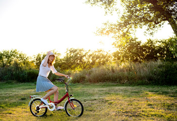 Beautiful young caucasian woman riding a bicycle in park at summer sunny day