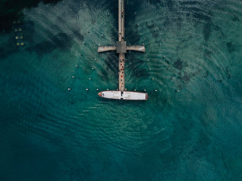 Boat on a clear lake with pier from drone