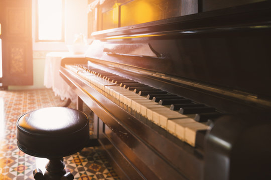 Old and cracked piano and stool with sunlight