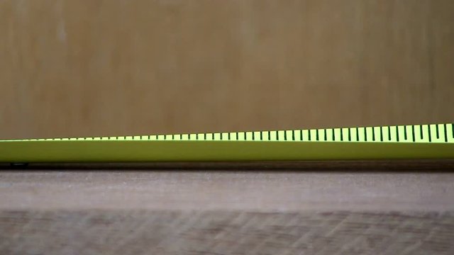 A tape measure is used to draw tick marks in maple board for cutting.  Macro shot from slight high angle looking down with wood background.