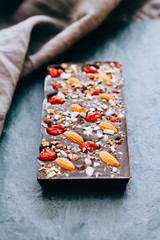 Raw homemade chocolate and candy with nuts, cranberris on black background