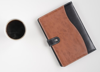 Coffee cup and notebook on white