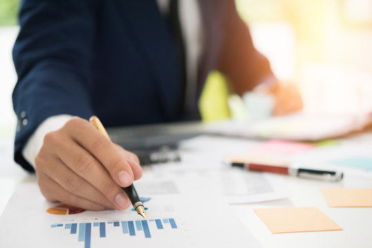 Businessman pen pointing graph chart in this mounth and use calculator for Plans to improve quality next month.